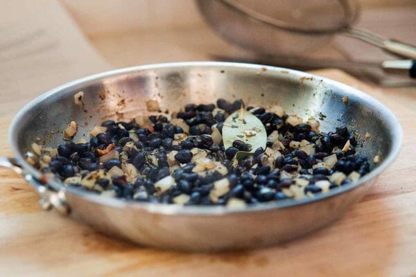 Black Bean Quinoa Bowl - Black beans with bay leaf and onion in skillet