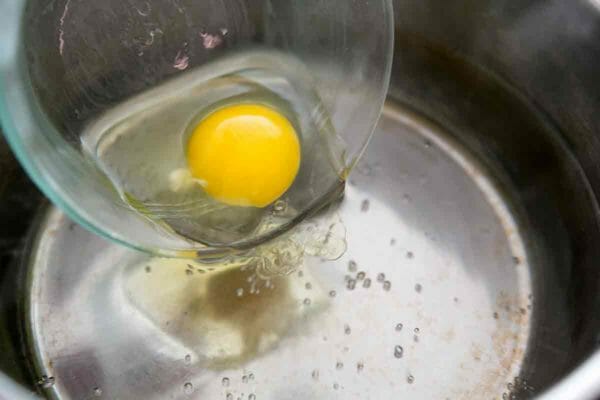 gently lower raw egg into the surface of the hot simmering water