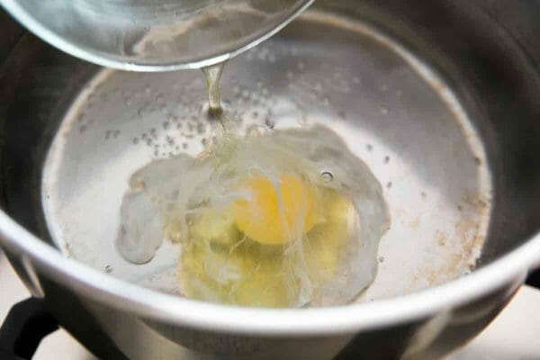 make poached eggs by putting raw egg into hot water