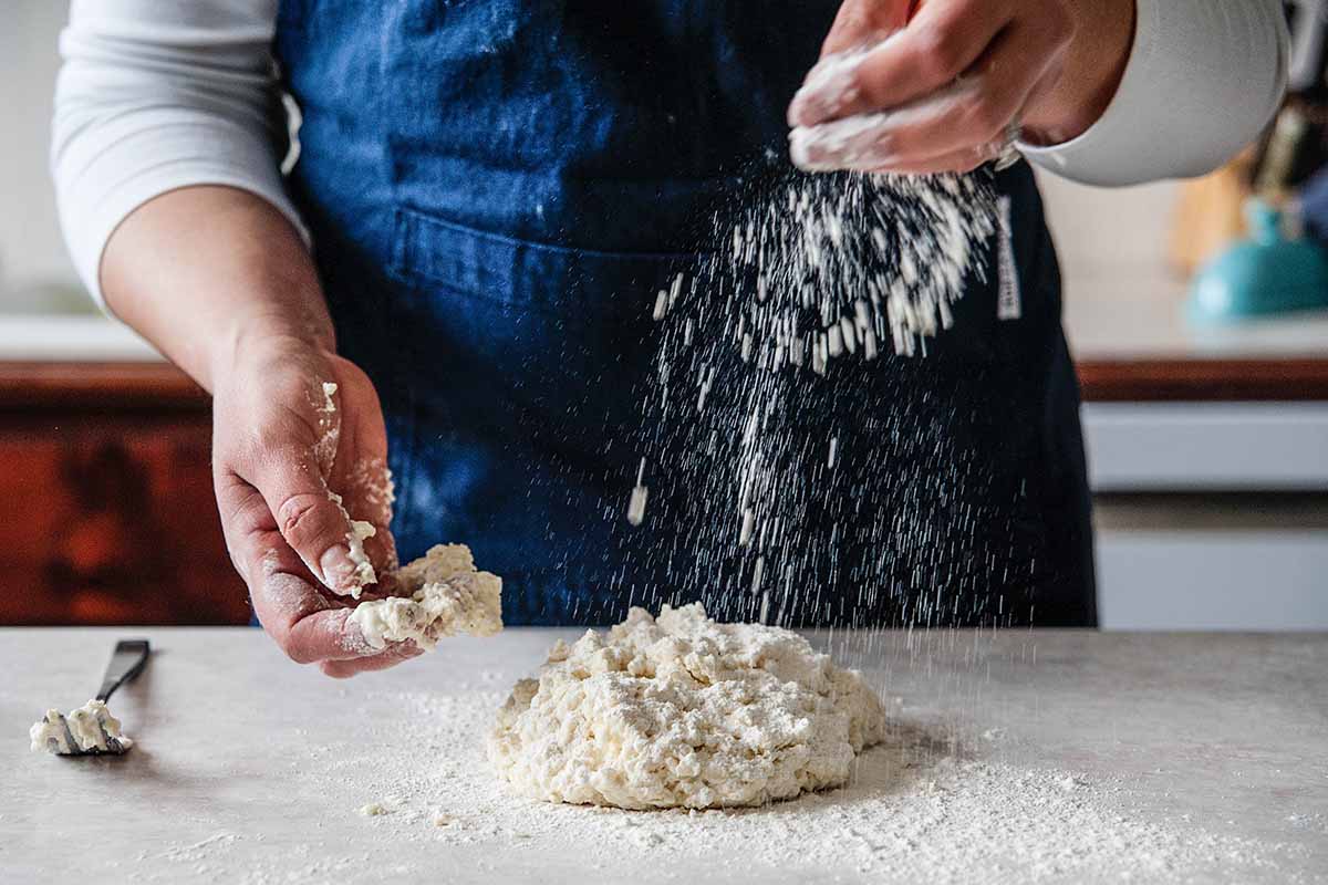 Southern buttermilk biscuits - woman sprinking flour on dough