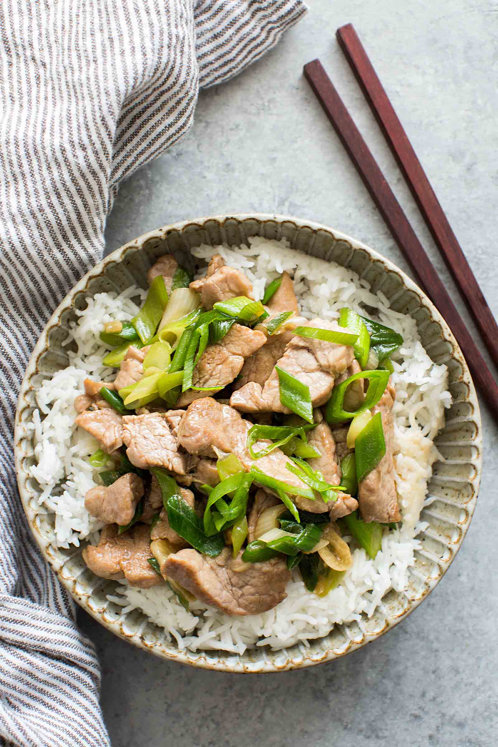 Pork Stir Fry with Green Onion in a bowl with chopsticks beside