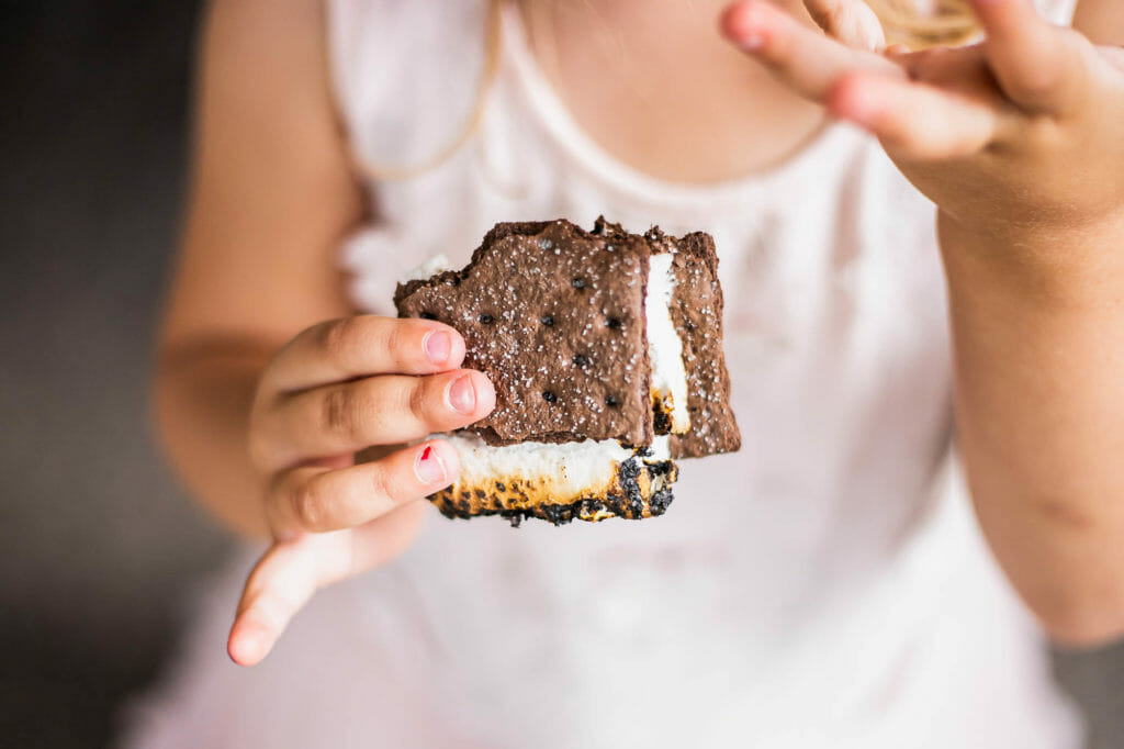 A child holds a chocolate graham cracker smore during a backyard Smores Party.