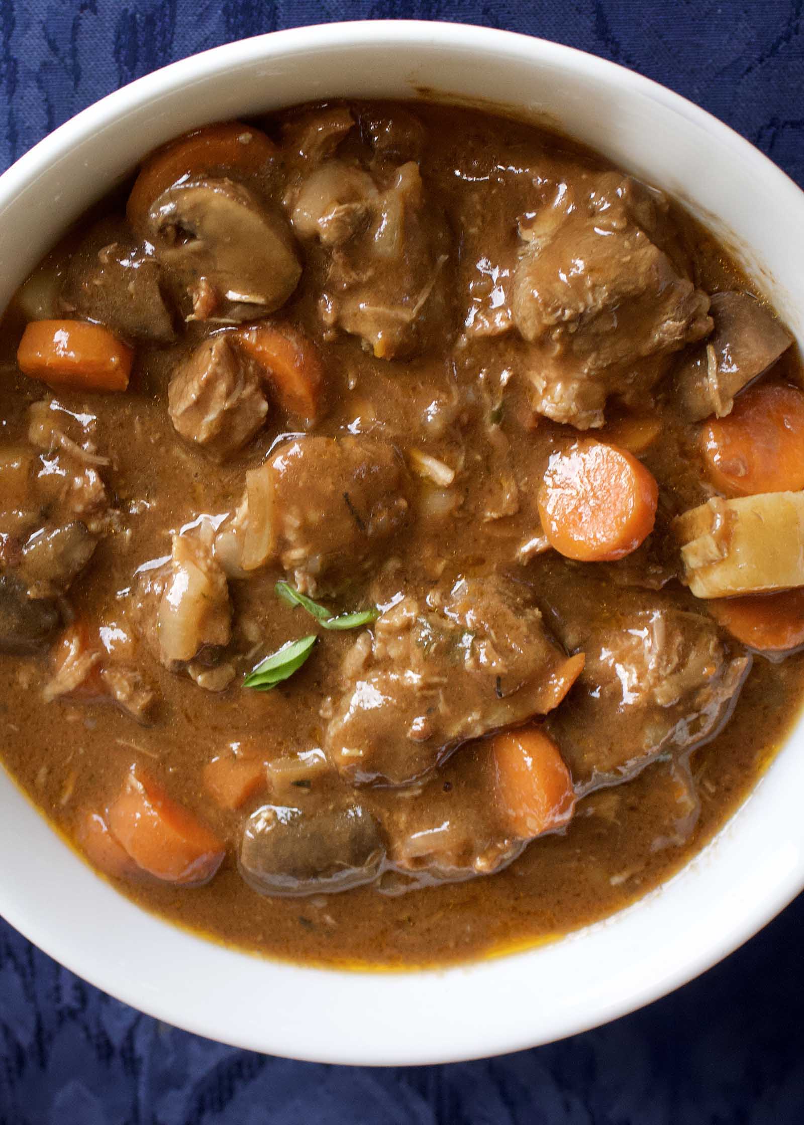 Slow Cooker Beef Stew with Mushrooms, Onions and Carrots in a white bowl.