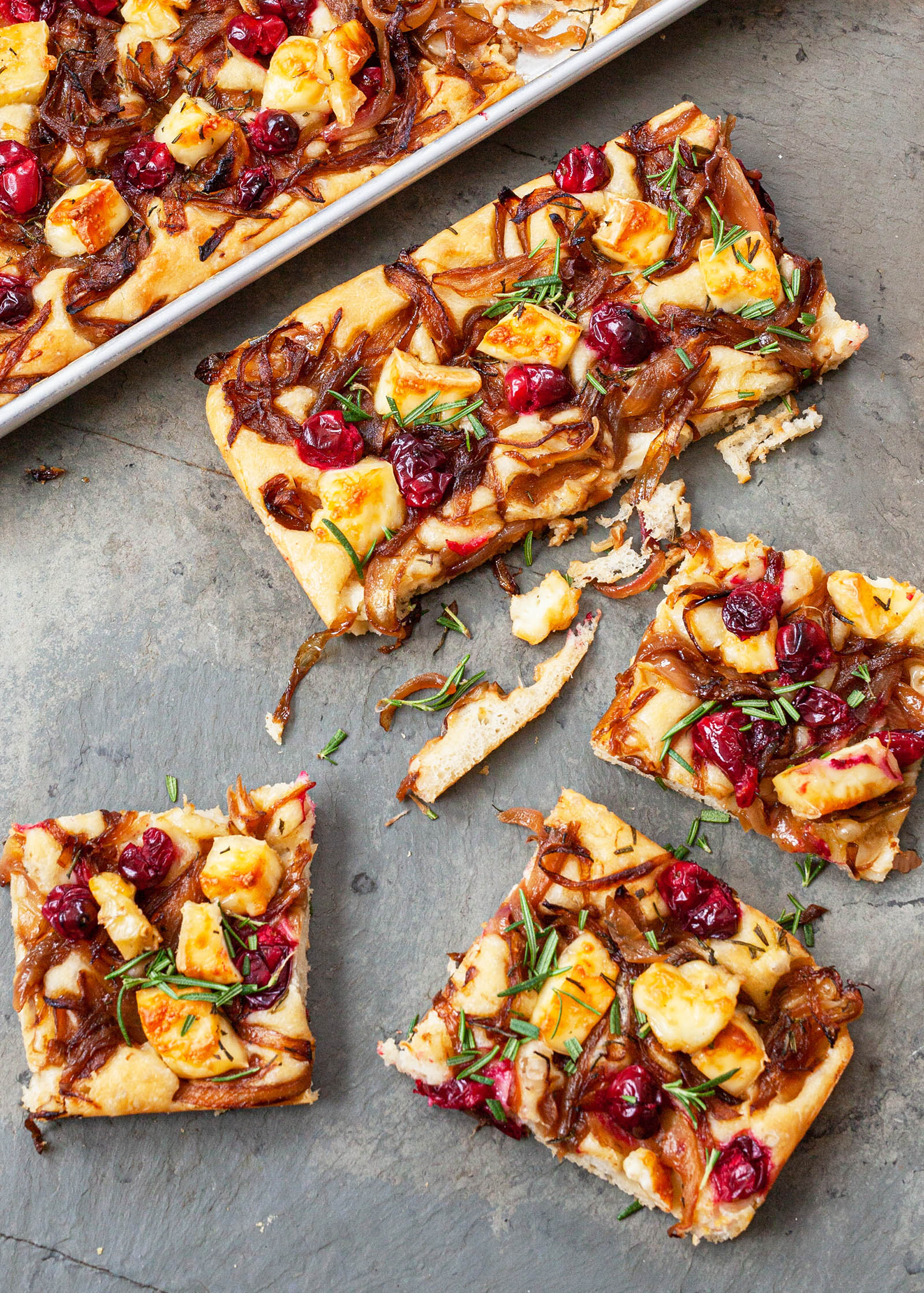 Slices of focaccia topped with caramelized onion, cranberry, and brie.