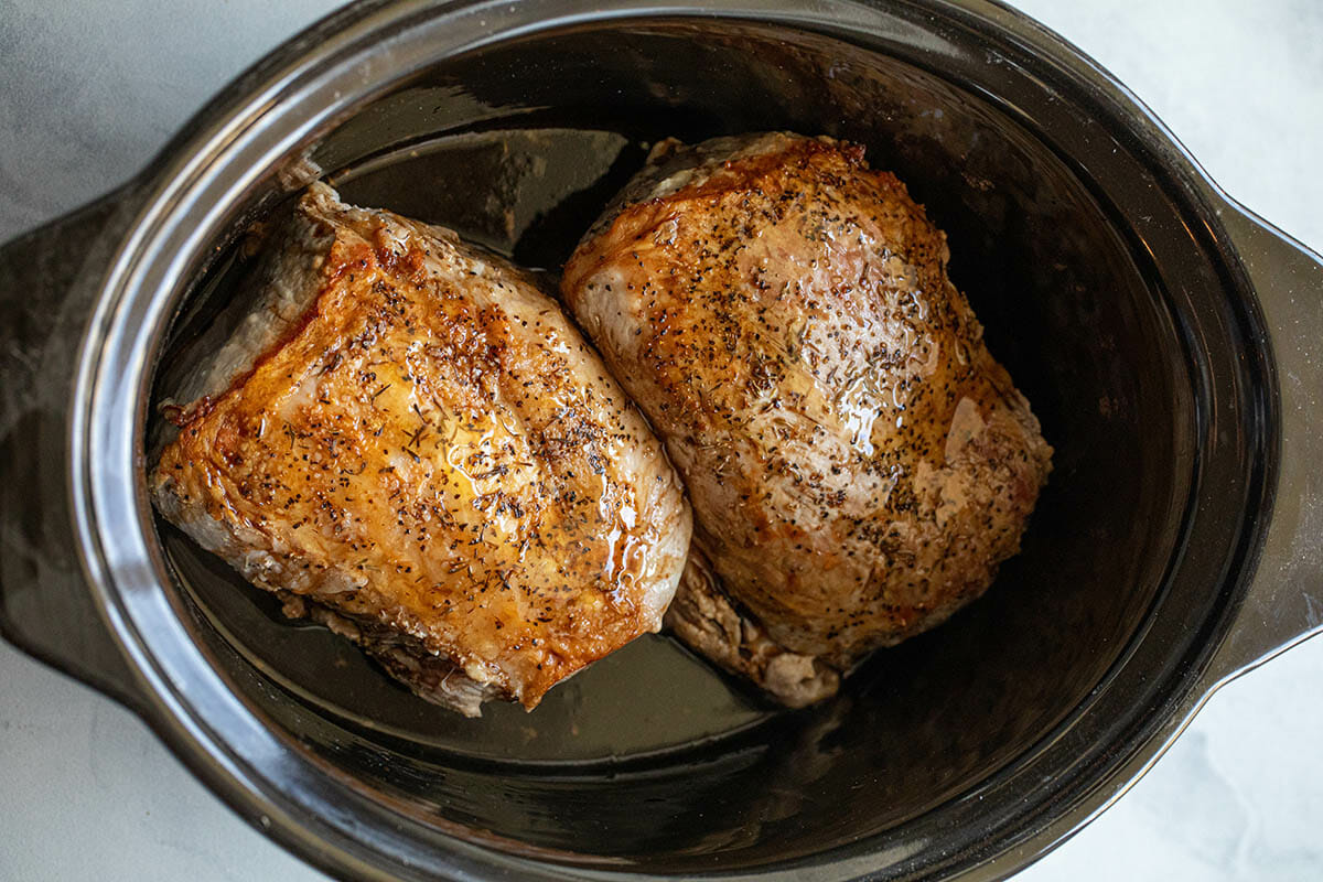 Two pork loins are set next to each other in a crock pot to show how to make slow cooker pork loin.
