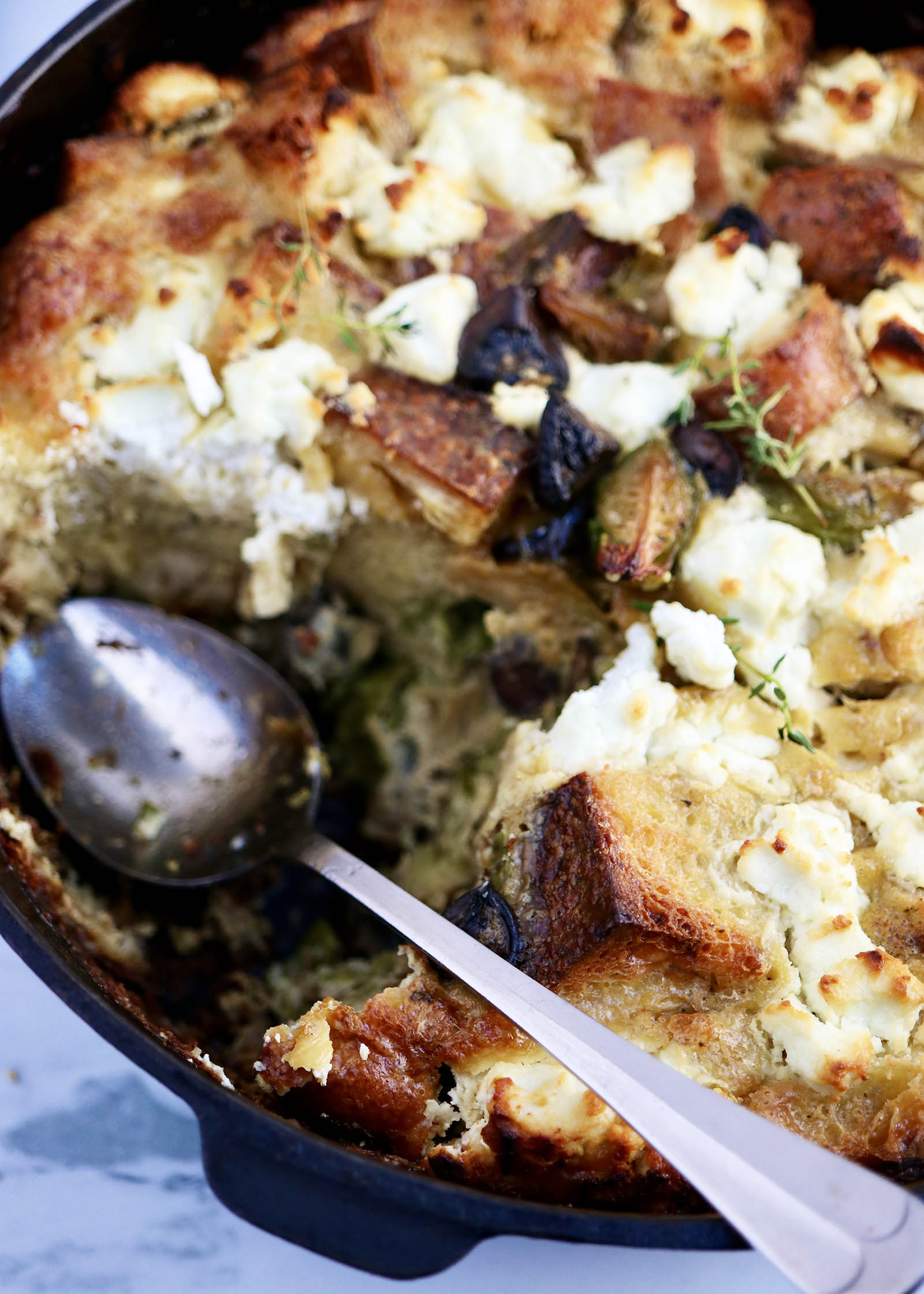 Overhead view of a Vegetarian Breakfast Casserole with Goat Cheese with a serving missing and spoon in its place.