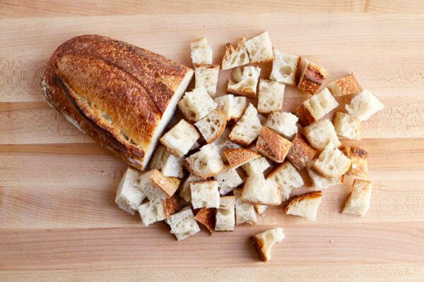 A crusty loaf of bread that is partially cut into cubes to make a Vegetarian Breakfast Casserole with Goat Cheese.