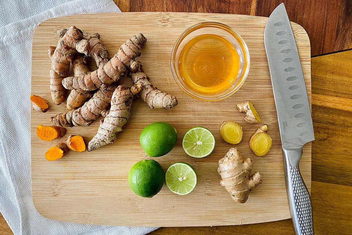Limes, ginger, turmeric, and honey on a cutting board to show how to make Jamu.